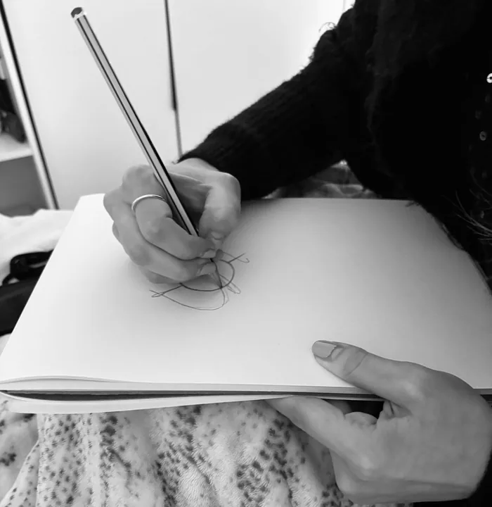 Una mano disegna a matita su un blocco
